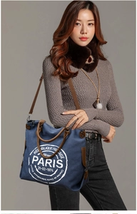 Detail of navy canvas tote bag with brown leather handles and vintage Paris emblem