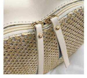 Detail of woven straw bag with dual metal zippers and cream PU leather pullers