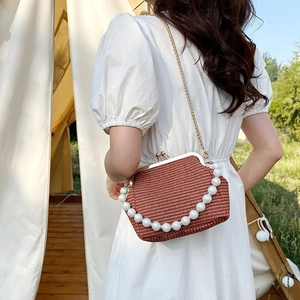 Detail view of a vintage woven shell bag with elegant white pearl accents and metal chain