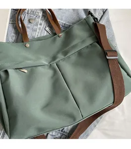 Dettaglio della borsa tote in nylon verde oliva con manici in pelle marrone e tasca zip