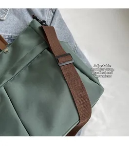 Dettaglio della tracolla regolabile in nylon marrone sulla borsa tote verde scuro