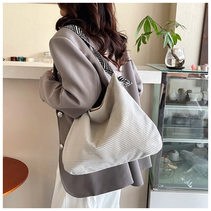Chic off-white corduroy tote bag with zebra print strap shown on shoulder in a cafe
