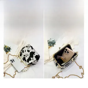 Cow print shell bag showing internal capacity with phone and cosmetics layout