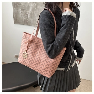 Model wearing a pink large tote bag with M letter monogram pattern and metal charm