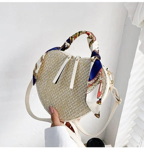 Detail view of heart-shaped woven straw bag with decorative silk scarf on handle
