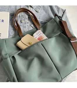Dettaglio della borsa tote in nylon grigio-verde con tasca frontale e manici in pelle marrone