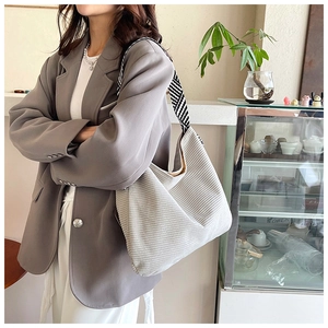 Close-up of gray corduroy tote bag featuring a striped woven shoulder strap for commuting