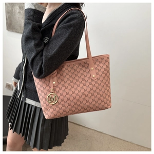 Detail of pink tote bag showing M-pattern leather texture and golden metal logo charm