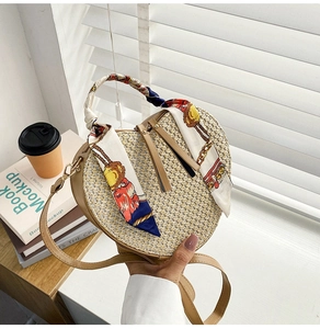 Detail view of heart-shaped woven beach bag with silk scarf handle and leather straps