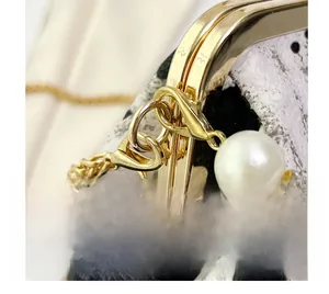Detail of gold hardware chain with pearl charm and rhinestone on textured shell bag