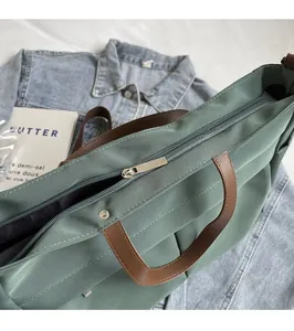 Dettaglio della borsa tote in nylon con manici in pelle e chiusura a zip in metallo liscio