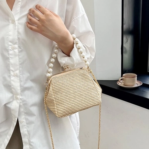 Detail of woven straw bag with pearl handle and gold chain strap in a French style setting