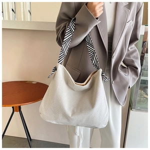 Detail view of cream corduroy hobo bag with geometric patterned strap on model