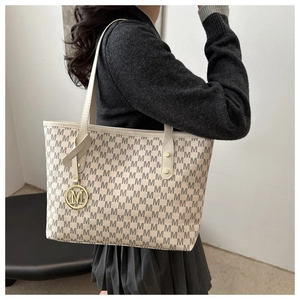Detail of minimalist tote bag featuring M-pattern jacquard and golden M logo charm
