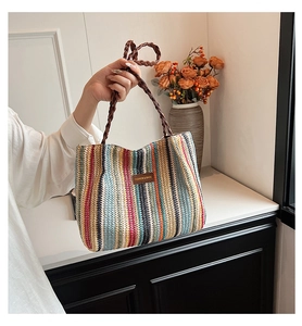Detailed macro of a woven tote bag featuring colorful vertical stripes and leather patch