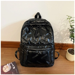 Détail d'un sac à dos noir brillant matelassé avec tirettes de fermeture tissées et nylon