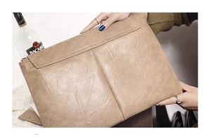 Détail macro du sac enveloppe en cuir PU tons terre avec texture plissée vintage et poche arrière