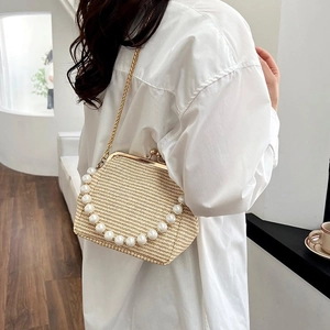 Detail view of woven straw shell bag with pearl handle and golden chain strap