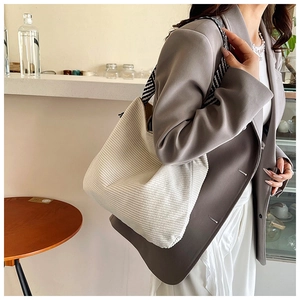 Detail of white corduroy tote bag featuring vertical texture and woven shoulder strap