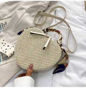 Detailed top view of a heart-shaped woven straw beach bag with a colorful silk scarf handle