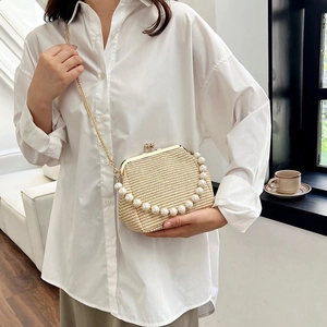 Detailed view of beige woven shell bag featuring a pearl handle and gold metal frame