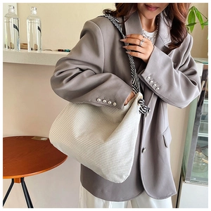Detail of white corduroy tote bag showing soft ribbed texture and striped strap