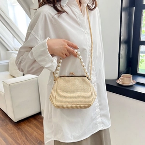 Detail of woven straw crossbody bag with pearl handle and golden chain strap