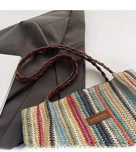 Detail of colorful striped woven tote bag with brown braided straps and fashion leather patch
