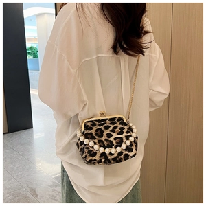 Detail of leopard print shell bag with pearl handle and golden chain on model side