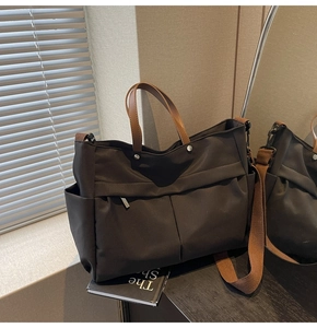 Dettaglio della borsa tote in nylon nero con manici in pelle marrone e rivetti in argento