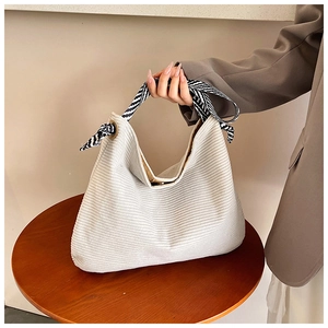 Corduroy tote bag in beige with a zebra pattern scarf on the handle shown on wood