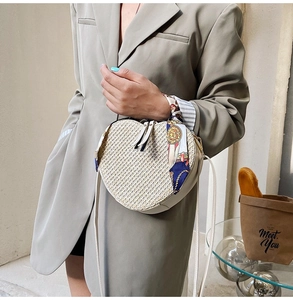 Detail of heart-shaped straw crossbody bag with white leather trim and ribbon handle