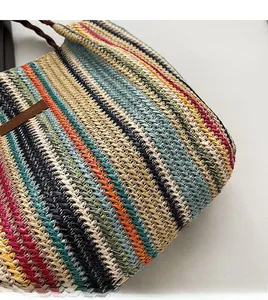 Close-up of woven straw tote showing colorful stripe texture and leather logo detail