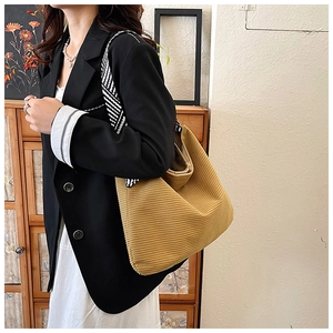 Detail of ginger corduroy tote bag featuring striped wide strap and soft texture