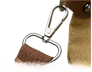 Detail of shiny metal lobster clasp and D-ring on a canvas shoulder strap connector