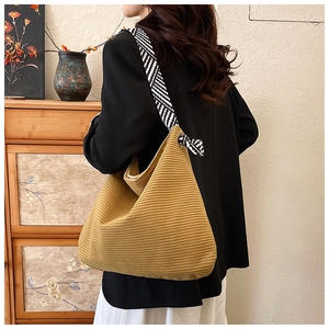 Detail of yellow corduroy tote bag featuring a geometric woven strap and soft ribbed texture