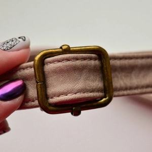 Close-up of vintage pink leather strap with textured grain and bronze metal buckle detail