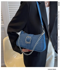 Dettaglio borsa a spalla in denim blu con cuciture bianche e tracolla a catena in metallo