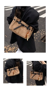Dettaglio di borsa tote in camoscio marrone con tracolle nere e nappine in perline