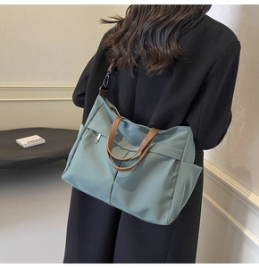 Vista dettagliata della borsa tote grande in nylon con manici in pelle su un modello