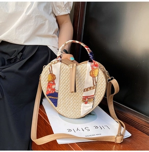 Detailed view of heart-shaped woven straw bag with silk scarf handle and leather strap