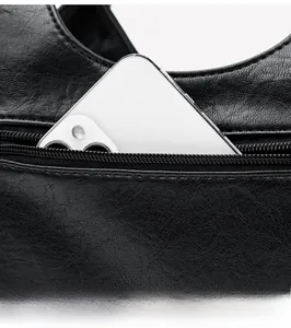 Detail view of the black leather bag zipper pocket holding a large smartphone
