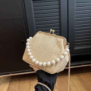 Detailed close-up of woven shell bag with large pearl handle and gold metal frame closure