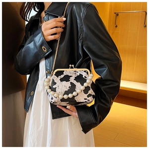Detail of cow print shell bag featuring a pearl handle and gold chain strap