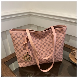 Detail of pink tote bag with M-letter monogram pattern and gold metal logo pendant