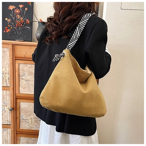 Detail of mustard yellow corduroy tote bag featuring a striped shoulder strap and bow