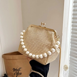 Detail of hand-woven straw bag featuring pearl handle and golden frame closure