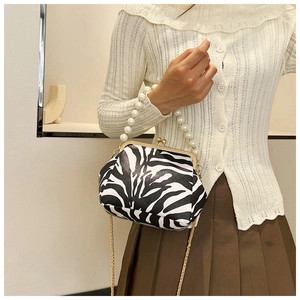 Detail of zebra pattern shoulder bag with faux pearl handle and gold clasp closure