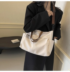 Dettaglio di una grande borsa tote in nylon beige con manici marroni e tasca