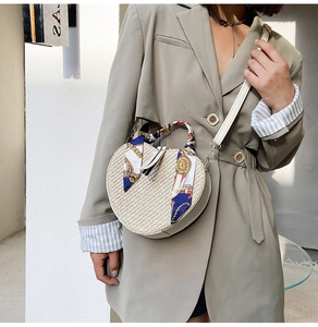 Detail of a heart-shaped straw bag with silk scarf handle and adjustable strap